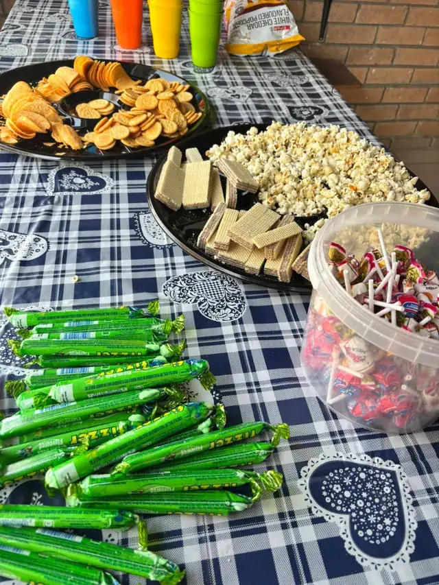 A party table with popcorn, crackers, wafers and sweets.