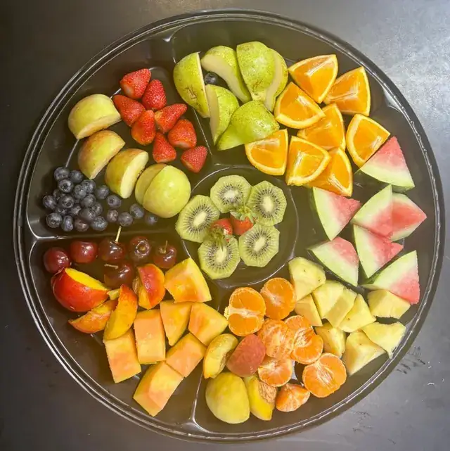 A round platter of sliced fresh fruit.