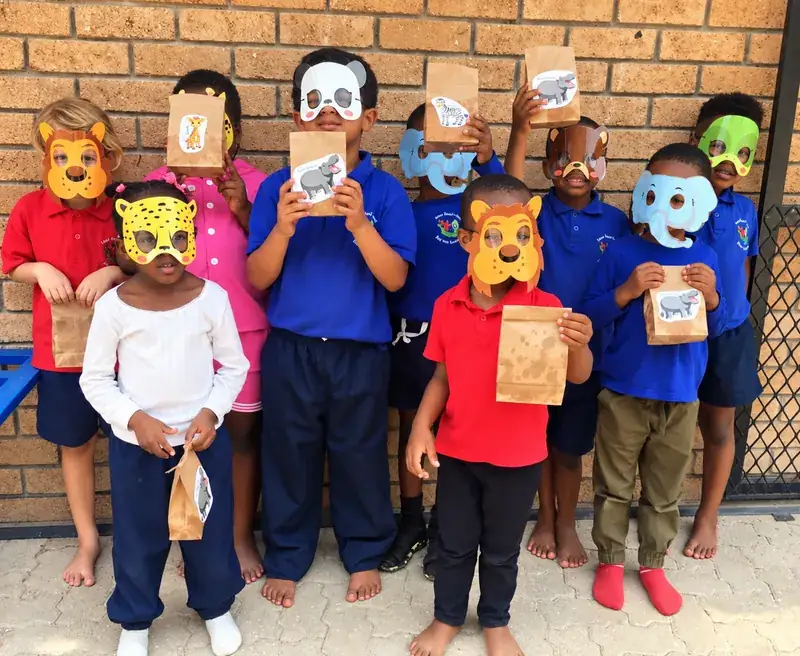 A group of children wearing paper animal masks and holding party bags.