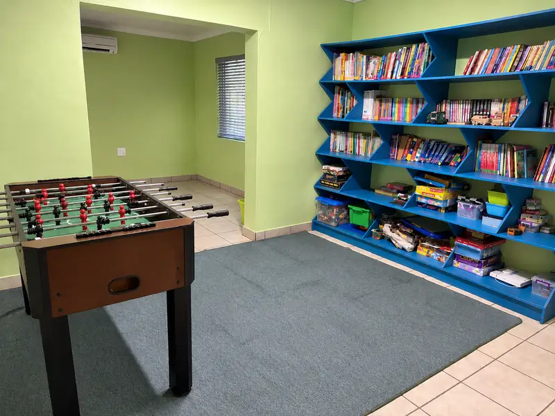 A reading corner with blue shelves full of books and a foosball table at our Okatana campus.