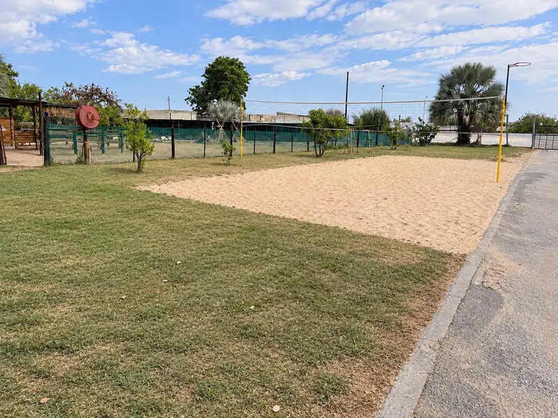 A wide lawn and sand play area with palm trees at our Okatana campus.
