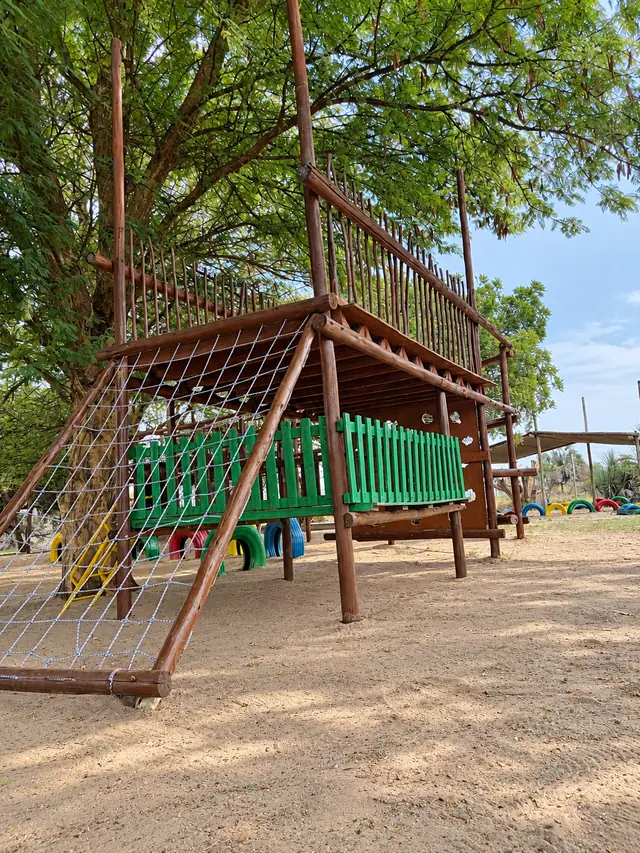 A wooden play fort with a rope climbing net at our Okatana campus.