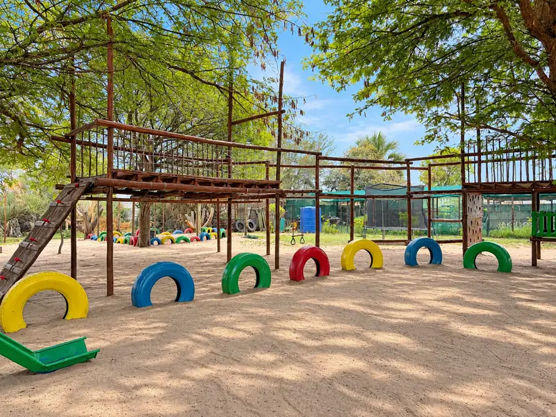 A long wooden jungle gym with a slide and a row of painted tyres at our Okatana campus.