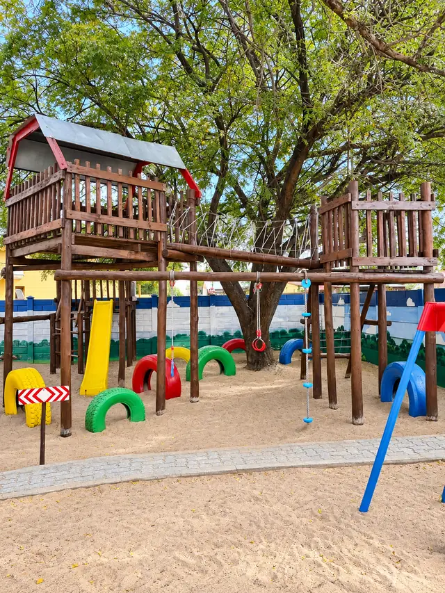 A wooden play fort with slides and a climbing frame at our Ongwediva campus.