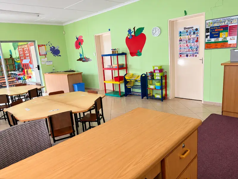 A classroom with group tables, a teacher&rsquo;s desk and a shapes chart at our Ongwediva campus.