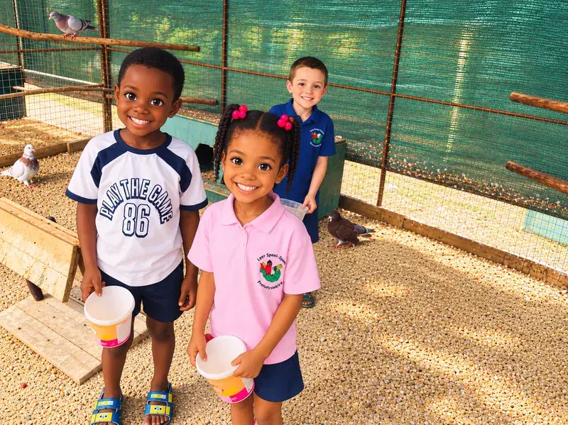 Three smiling children with feed cups in the bird enclosure.