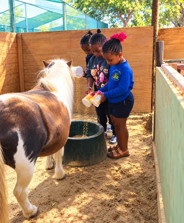 Children pouring feed into a pony's trough.