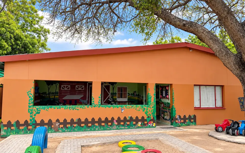 The orange classroom building at our Ongwediva campus, with painted tyres in the front play area.